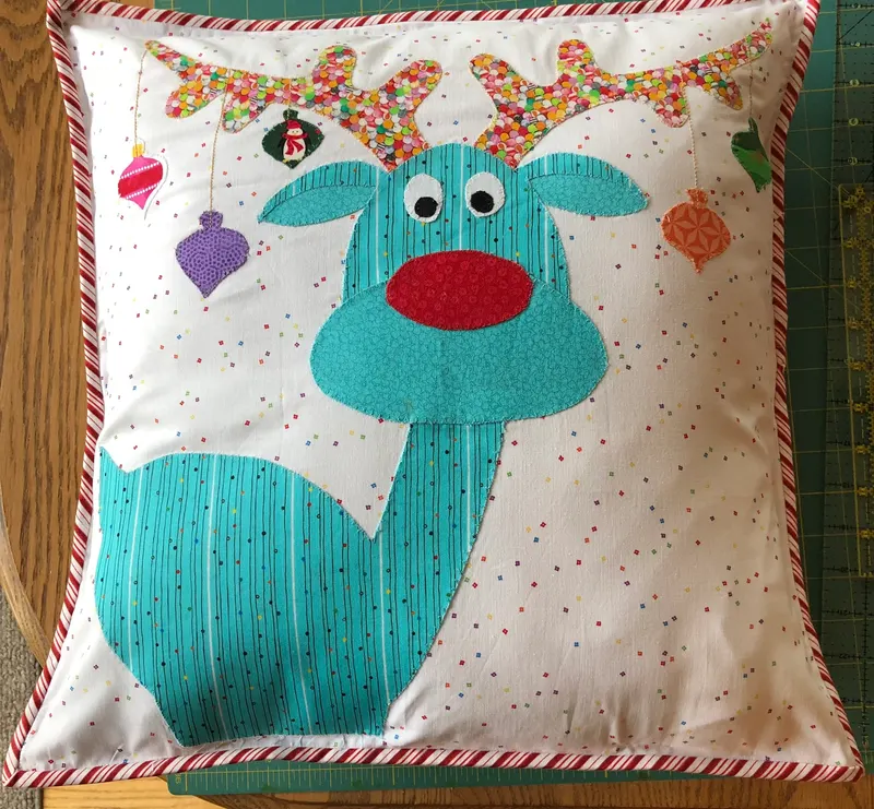 Whimsical reindeer pillow with ornaments on antlers