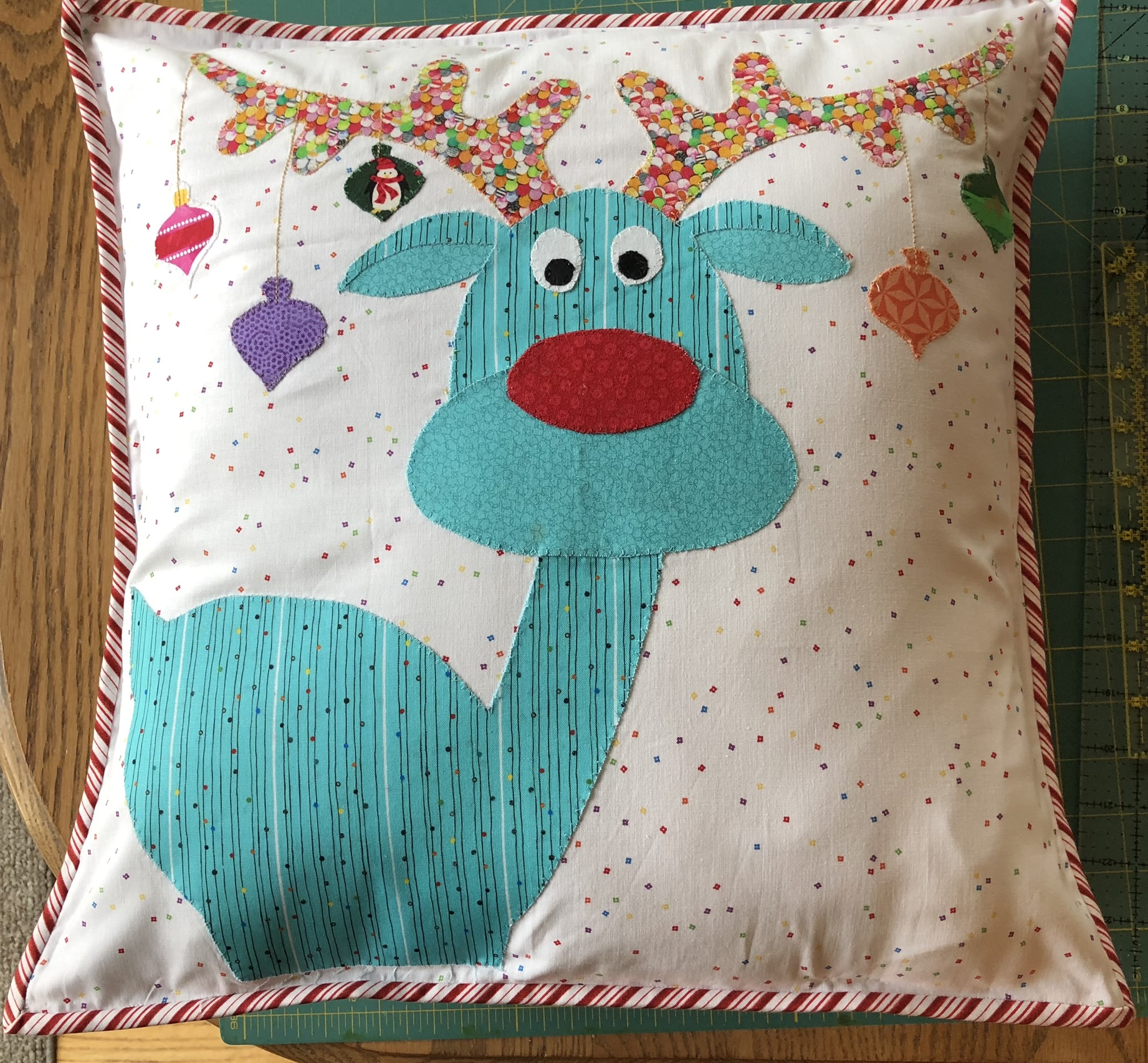 Whimsical reindeer pillow with ornaments on antlers