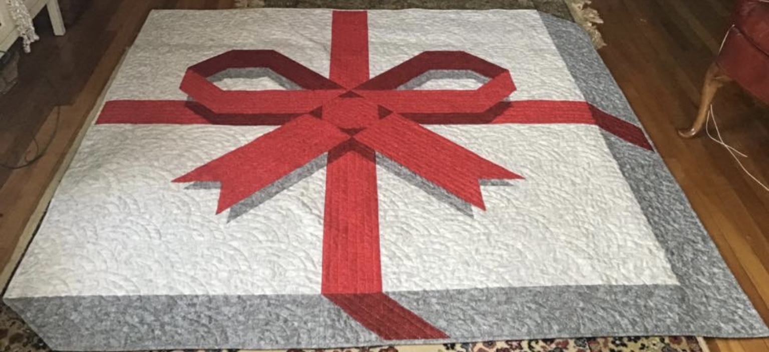 White quilt with big red ribbon and bow design