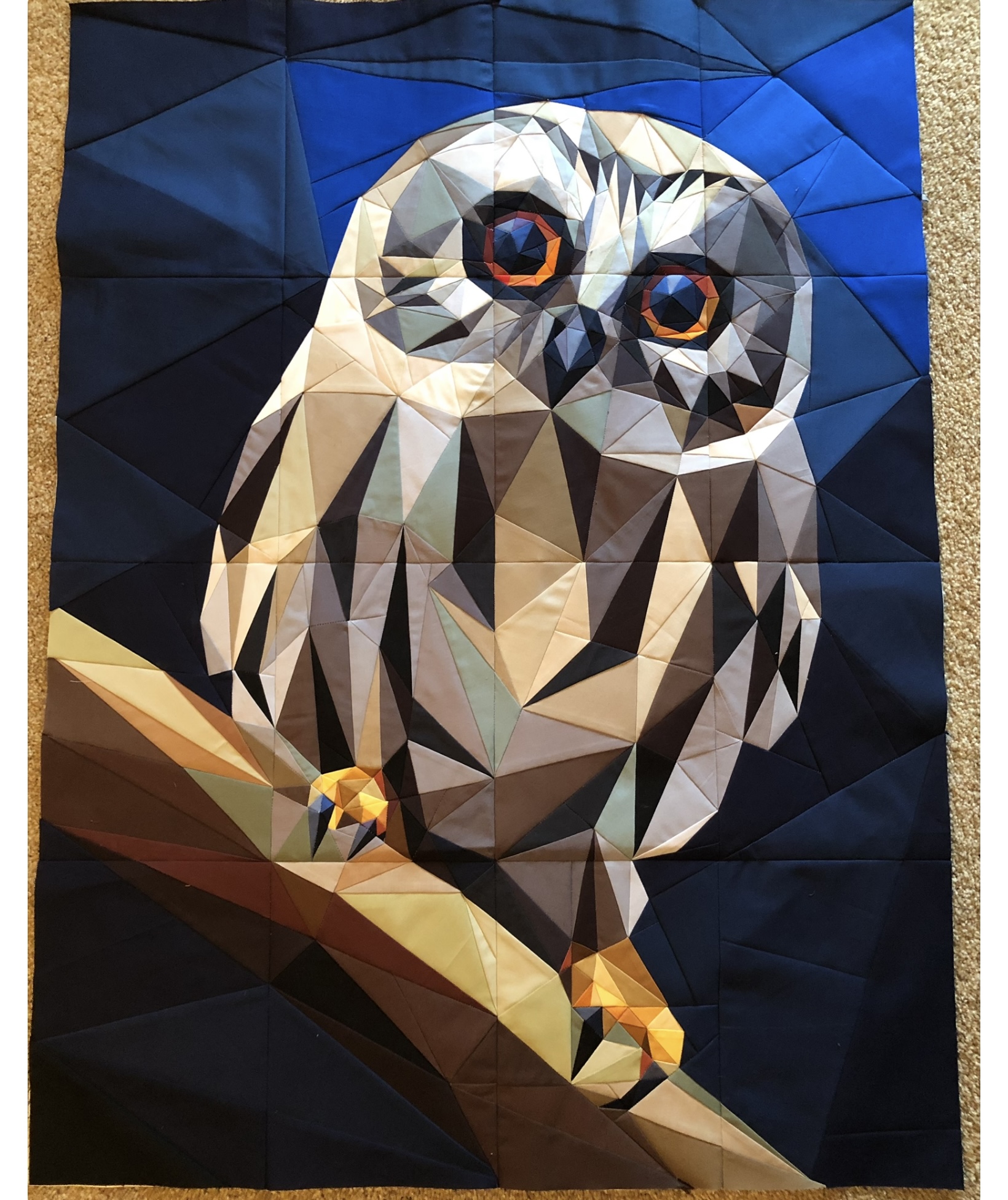 Owl perched on branch with large orange eyes