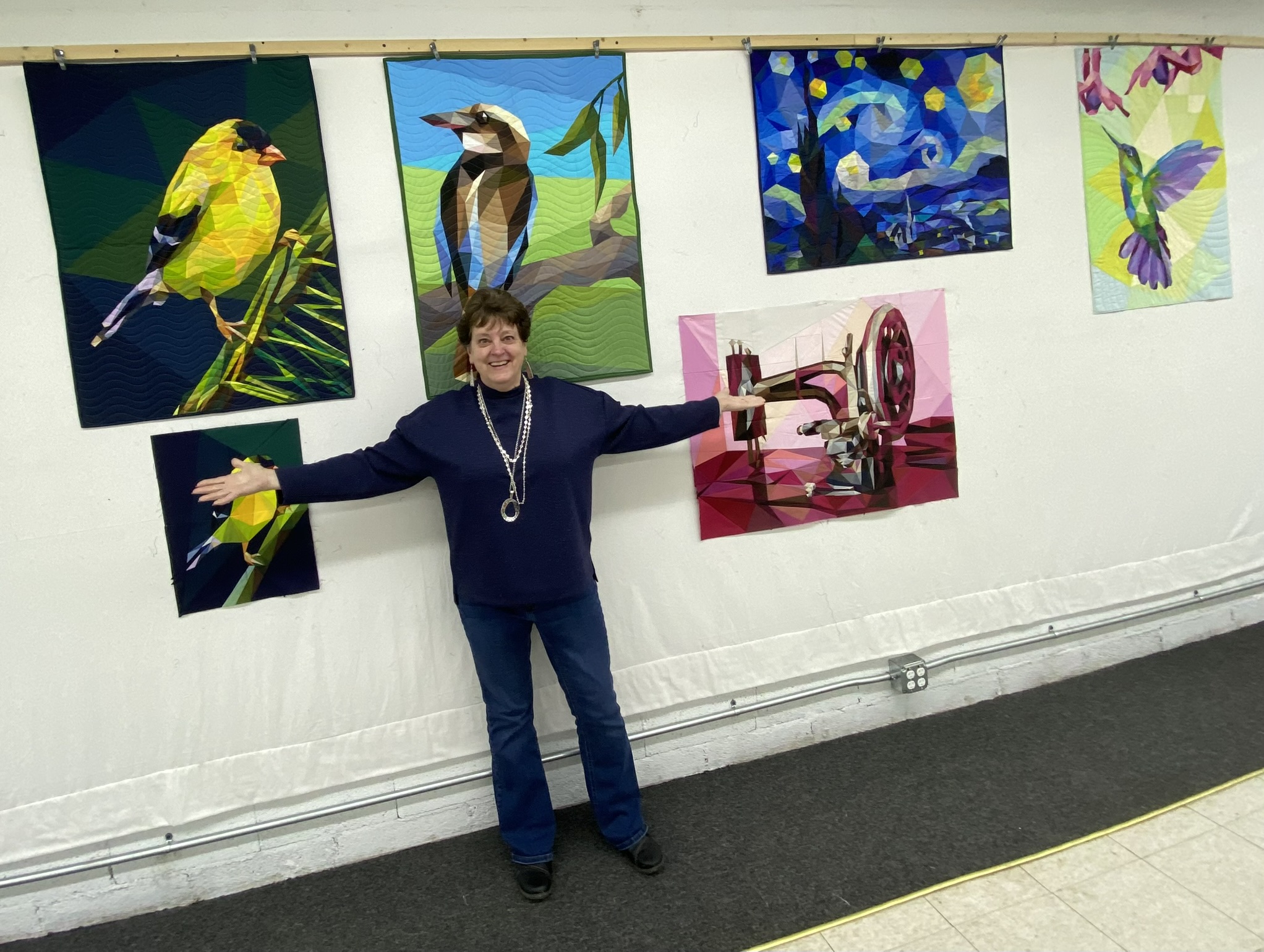 Mary Ellen with goldfinch, kookaburra, and starry night quilts at show